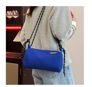 Blue mesh cylindrical crossbody bag with woven rope shoulder strap worn by model