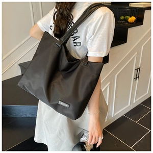 Detailed side view of a minimalist large capacity black tote bag on a model in a stairwell