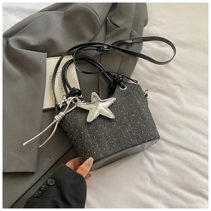 Detailed macro view of dark grey denim bucket bag with sparkling rhinestones and star charm