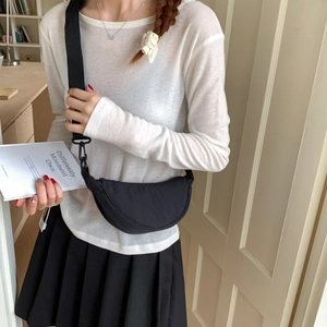 Detail of a black nylon crescent crossbody bag with adjustable wide strap on model