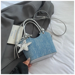 Detail of blue denim bucket bag featuring silver leather trim and a star charm