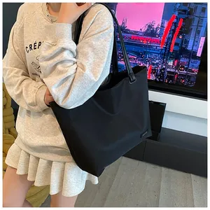 Detail of a black large-capacity tote bag worn over the shoulder in a casual setting