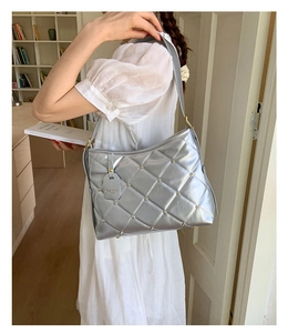 Detailed view of silver quilted shoulder bag with metallic studs and fashion tag