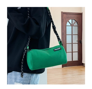 Detail of green barrel bag with textured fabric and stylish black-and-white woven strap