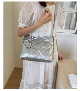 Close-up of quilted silver chain bag featuring golden rivets and metallic texture