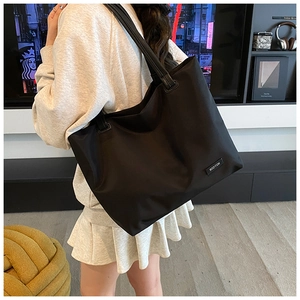 Detail view of the large black nylon tote bag showing the side strap and brand label