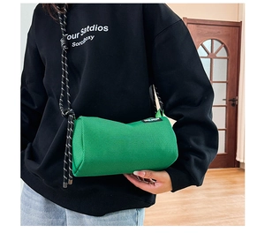 Detail view of a bright green cylindrical canvas bag with a striped woven strap
