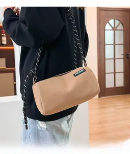 Detail of khaki mesh cylindrical crossbody bag with woven rope strap on a model