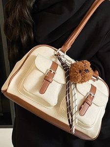Retro canvas and leather shoulder bag with bear charm shown on a model in a side view