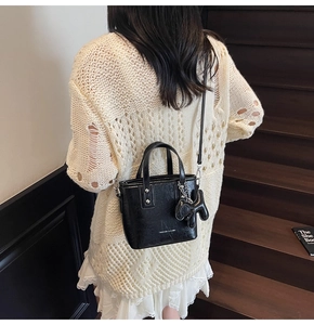 Detail of a chic black bucket bag with a cute animal charm in a lifestyle setting