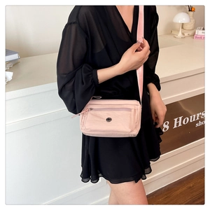 Detail view of pink nylon crossbody bag with multiple zip pockets and wide shoulder strap