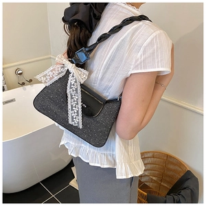 Detail of black glitter shoulder bag with lace bow and leather braided strap
