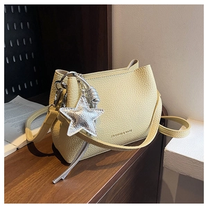 Détail du sac seau jaune avec texture litchi et pendentif étoile argentée