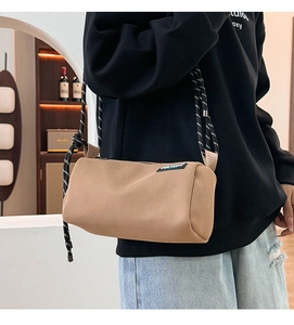 Detail view of khaki mesh cylinder crossbody bag with black and white climbing rope strap