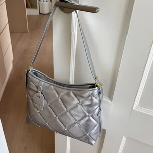 Detail of silver quilted chain bag with rhinestone accents and metallic finish