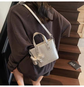 Detail of silver metallic mini tote bag with puppy charm and adjustable strap