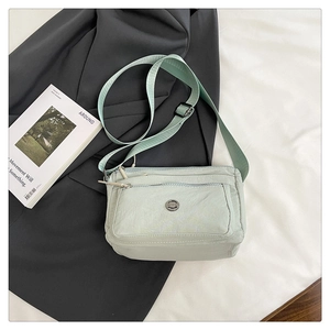 Detailed macro view of mint green nylon crossbody bag with metal logo and multi-pocket design