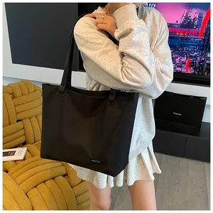 Detailed view of black nylon tote bag with brand label in a daily lifestyle setting