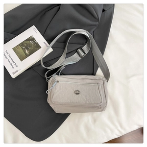 Close-up of light gray nylon crossbody bag showing water-resistant fabric and zippers