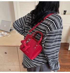 Detail of red glossy square handbag with cute dog charm and silver chain strap