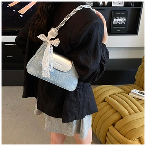 Detail view of the silver glitter underarm bag featuring a woven strap and large lace bow