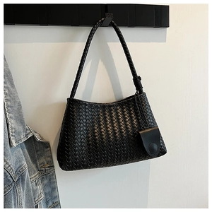 Close-up of black woven shoulder bag featuring a matching round coin purse detail