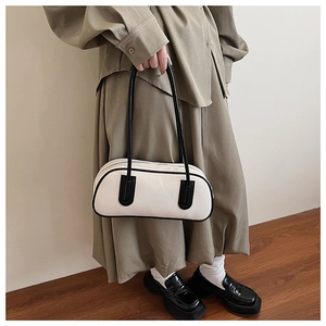 Minimalist black and white bowling bag detail with long shoulder straps and leather trim