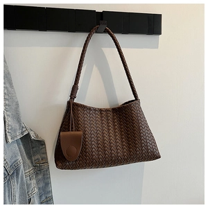 Close-up of dark brown woven leather shoulder bag with intricate Intrecciato texture