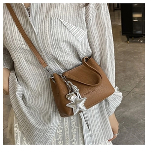Sac seau en cuir marron avec pendentif étoile présenté dans un look de rue moderne