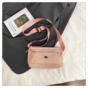 Detailed macro view of pink nylon fabric texture and adjustable strap on cross-body bag