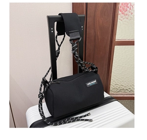 Close-up of black cylinder mesh crossbody bag featuring wide padded woven shoulder strap