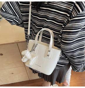 Detail of white wrinkled leather bucket bag with silver studs and cute dog charm
