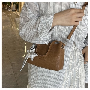 Gros plan du sac bandoulière en cuir marron avec breloque étoile argentée et gaufrage
