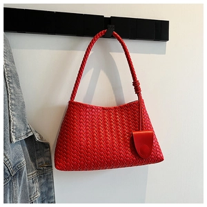 Close-up of red leather woven underarm bag showcasing intricate hand-knitted texture and handle