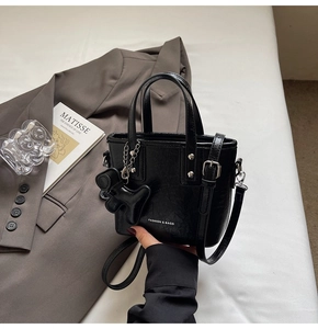 Detail of black glossy mini bucket bag with silver studs and a cute animal charm
