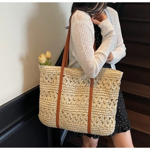 Detailed macro view of the floral crochet pattern and leather straps on the straw tote bag