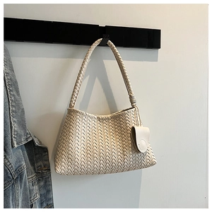 Close-up of cream hand-woven hobo bag with thick straps hanging on a metal hook