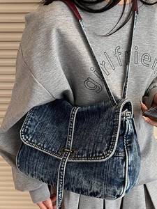 Washed blue denim messenger bag with white contrast stitching and metal twist lock