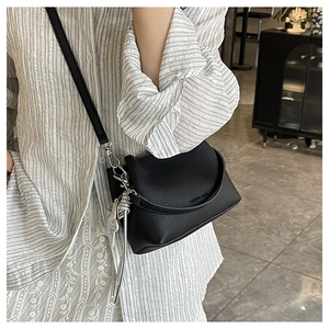 Détail du sac seau en cuir grainé noir avec pompon argenté et gravure de mode