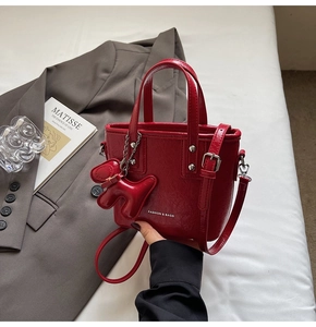 Detail of red glossy bucket bag with cute dog charm and detachable shoulder strap