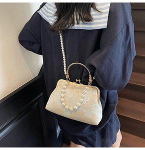 Detail view of vintage jacquard handbag featuring elegant gold patterns and pearl handle