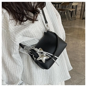 Détail du sac bandoulière en cuir grainé noir avec pendentif étoile argentée et bandoulière