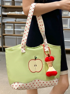 Green apple tote bag with red polka dot straps and a cute plush charm on a model