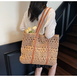 Detail showing the intricate hollow weave pattern and premium brown leather straps on tote
