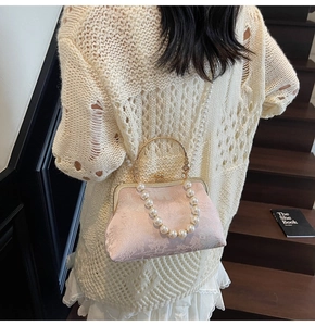Close-up of pink floral embroidery bag with pearl strap and golden clasp detailing