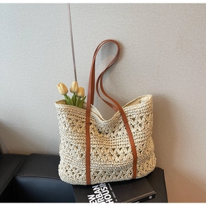 Detail showing hollow flower weave texture and brown leather strap on cream straw tote bag