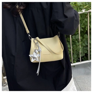 Détail du sac à bandoulière crème avec texture litchi et breloque étoile à franges