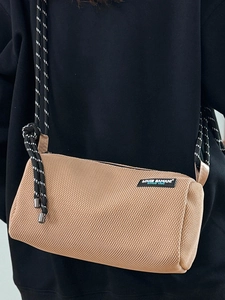 Khaki cylinder canvas crossbody bag with mesh texture and sporty black and white rope strap