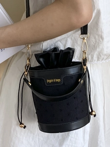 Sac seau noir chic avec texture contrastée, fermeture à cordon et détails dorés