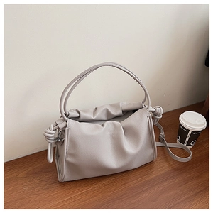 Detail view of the soft pleats and decorative side knots on the light grey cloud bag